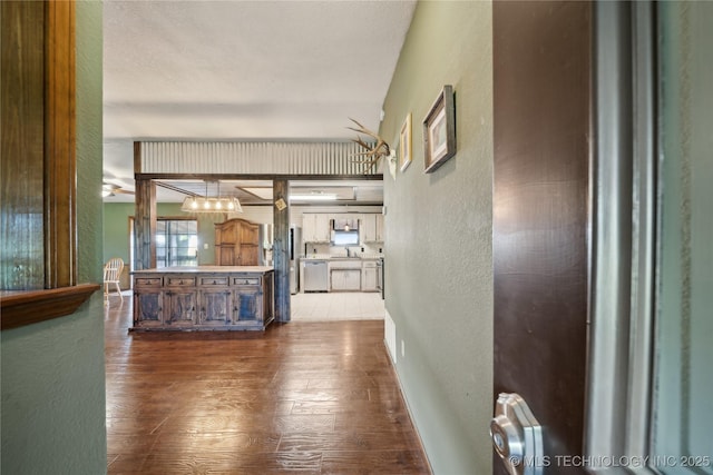 1202 S Oak Grove Rd, Cushing, OK 74023 - corridor featuring a textured wall, dark wood-style flooring, a sink, and baseboards