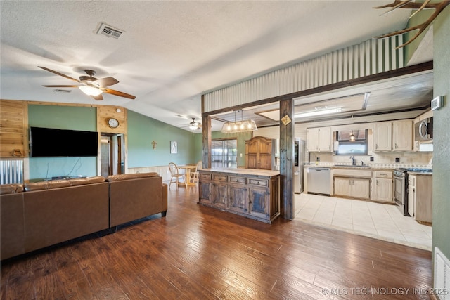 1202 S Oak Grove Rd, Cushing, OK 74023 - living room with a ceiling fan, lofted ceiling, light wood finished floors, a wainscoted wall, and a textured ceiling