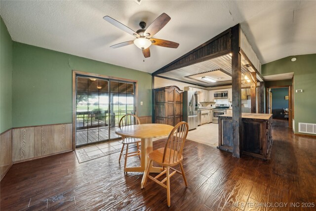 1202 S Oak Grove Rd, Cushing, OK 74023 - dining space featuring ceiling fan, wainscoting, wood finished floors, lofted ceiling, and wooden walls