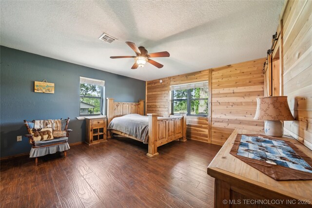 1202 S Oak Grove Rd, Cushing, OK 74023 - bedroom with wooden walls, dark wood-type flooring, a textured ceiling, a ceiling fan, and baseboards