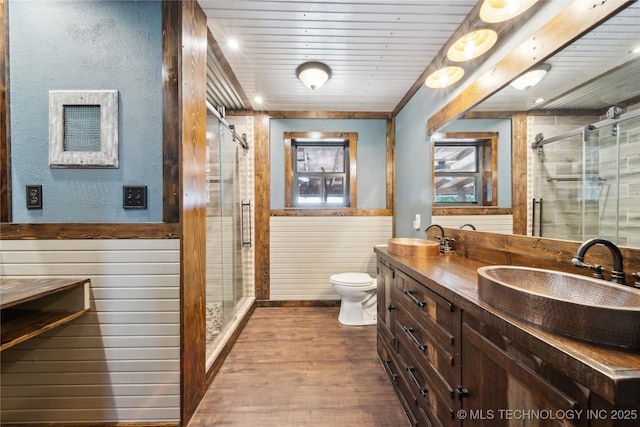 1202 S Oak Grove Rd, Cushing, OK 74023 - full bath with toilet, double vanity, wood finished floors, a stall shower, and wood walls