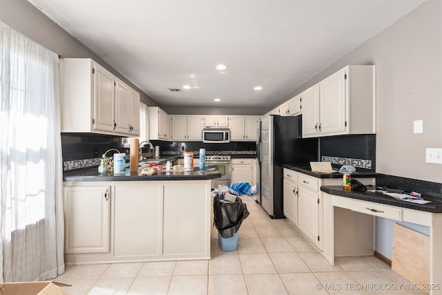18268 S 79th E Ave, Bixby, OK 74008 - kitchen with stainless steel appliances, dark countertops, a peninsula, light tile patterned flooring, and white cabinets
