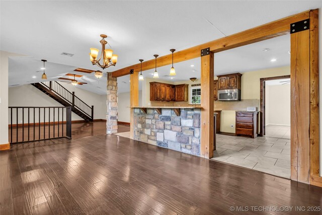 2382 Cheek, Lone Grove, OK 73443 - kitchen featuring stainless steel microwave, open floor plan, beam ceiling, a chandelier, and ornate columns