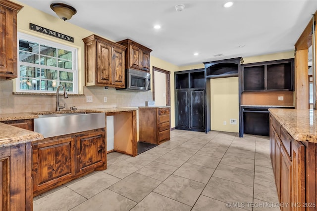 2382 Cheek, Lone Grove, OK 73443 - kitchen featuring stainless steel microwave, decorative backsplash, light stone counters, light tile patterned floors, and recessed lighting