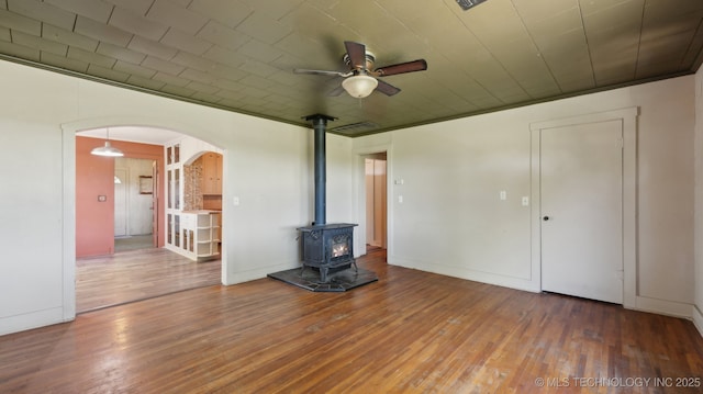 7941 N 433rd Rd, Adair, OK 74330 - unfurnished living room featuring a ceiling fan, arched walkways, a wood stove, and wood-type flooring