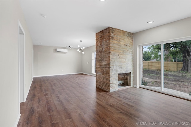 1550 E Apache St N, Tulsa, OK 74106 - unfurnished living room featuring an AC wall unit, a chandelier, wood finished floors, a stone fireplace, and baseboards