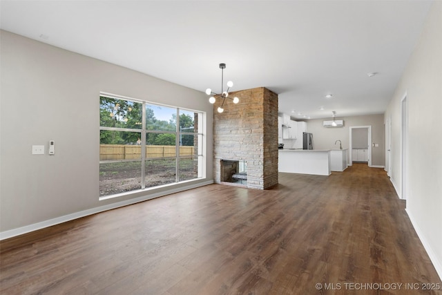 1550 E Apache St N, Tulsa, OK 74106 - unfurnished living room with a chandelier, dark wood-style floors, baseboards, recessed lighting, and a fireplace