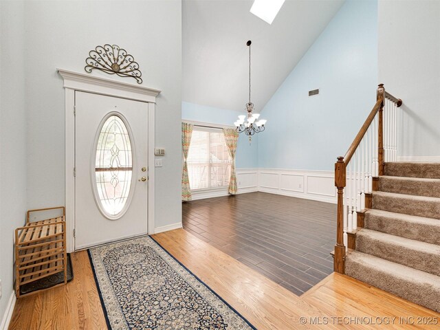8704 N 140th E Ct, Owasso, OK 74055 - entryway featuring wood finished floors, high vaulted ceiling, a chandelier, stairs, and a skylight