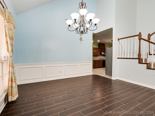 8704 N 140th E Ct, Owasso, OK 74055 - empty room featuring a chandelier, dark wood-style floors, stairs, wainscoting, and high vaulted ceiling