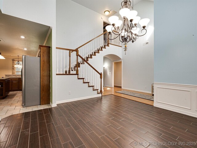 8704 N 140th E Ct, Owasso, OK 74055 - interior space featuring high vaulted ceiling, arched walkways, wood finished floors, stairs, and a chandelier