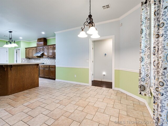 8704 N 140th E Ct, Owasso, OK 74055 - kitchen featuring under cabinet range hood, backsplash, pendant lighting, baseboards, and a breakfast bar area
