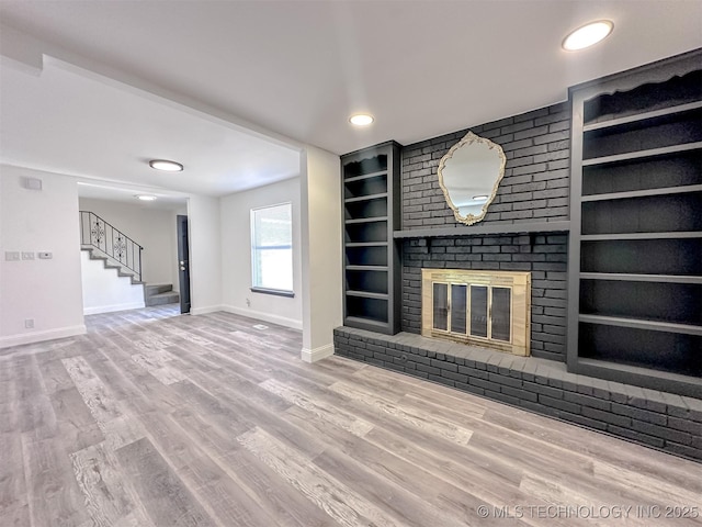 2212 W Independence Pl, Tulsa, OK 74127 - unfurnished living room featuring baseboards, built in features, stairway, a brick fireplace, and wood finished floors