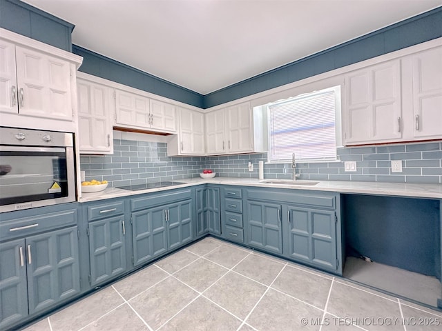 2212 W Independence Pl, Tulsa, OK 74127 - kitchen with stainless steel oven, a sink, black electric stovetop, light countertops, and decorative backsplash