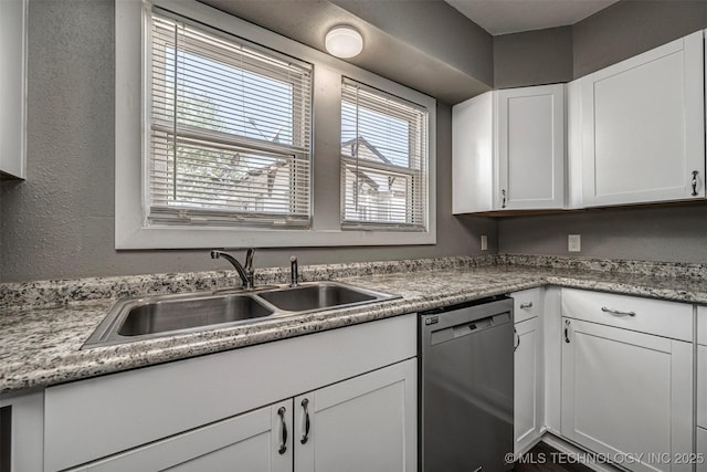 423 E Cherry St, Cushing, OK 74023 - kitchen featuring stainless steel dishwasher, a sink, white cabinetry, a textured wall, and light countertops