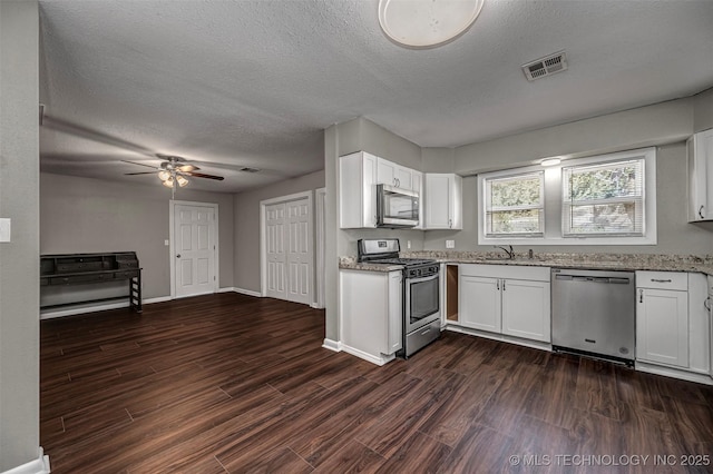 423 E Cherry St, Cushing, OK 74023 - kitchen with stainless steel appliances, a sink, a textured ceiling, light stone counters, and dark wood-style flooring