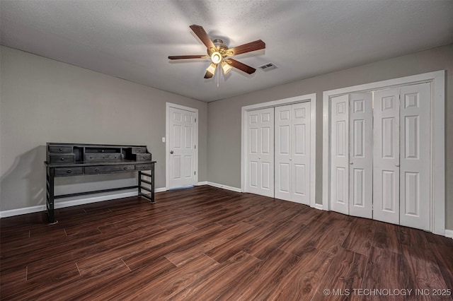 423 E Cherry St, Cushing, OK 74023 - unfurnished bedroom featuring two closets, wood finished floors, baseboards, a ceiling fan, and a textured ceiling