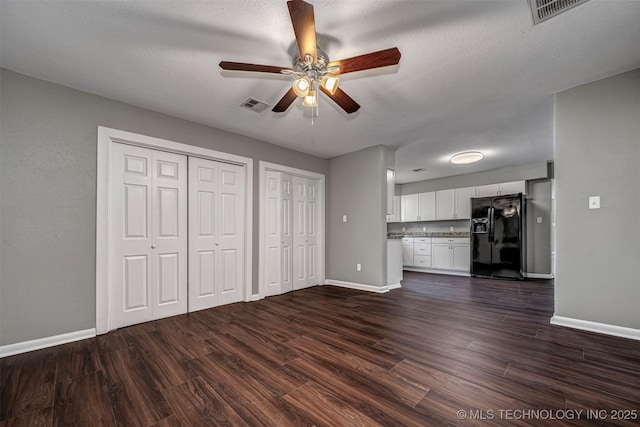 423 E Cherry St, Cushing, OK 74023 - unfurnished living room featuring baseboards, a ceiling fan, and dark wood finished floors