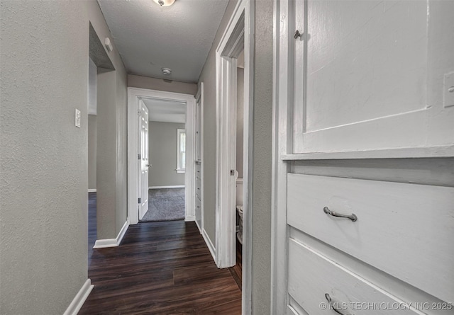 423 E Cherry St, Cushing, OK 74023 - corridor featuring dark wood-type flooring, baseboards, a textured wall, and a textured ceiling