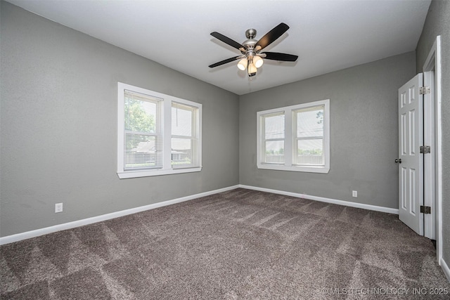 423 E Cherry St, Cushing, OK 74023 - unfurnished bedroom featuring multiple windows, dark carpet, baseboards, and ceiling fan