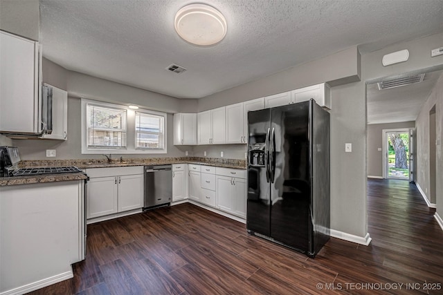 423 E Cherry St, Cushing, OK 74023 - kitchen with appliances with stainless steel finishes, a sink, dark wood-type flooring, white cabinetry, and a textured ceiling