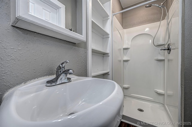 423 E Cherry St, Cushing, OK 74023 - bathroom featuring a sink, a shower stall, and a textured wall