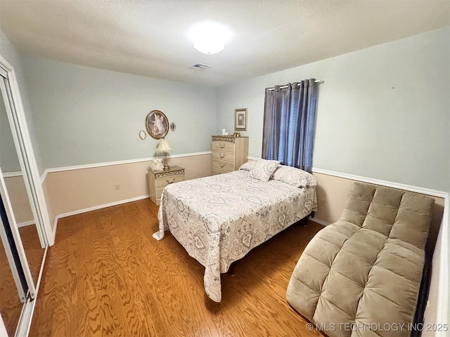 510 Beverly Ave, Vian, OK 74962 - bedroom with wood finished floors, a textured ceiling, and baseboards