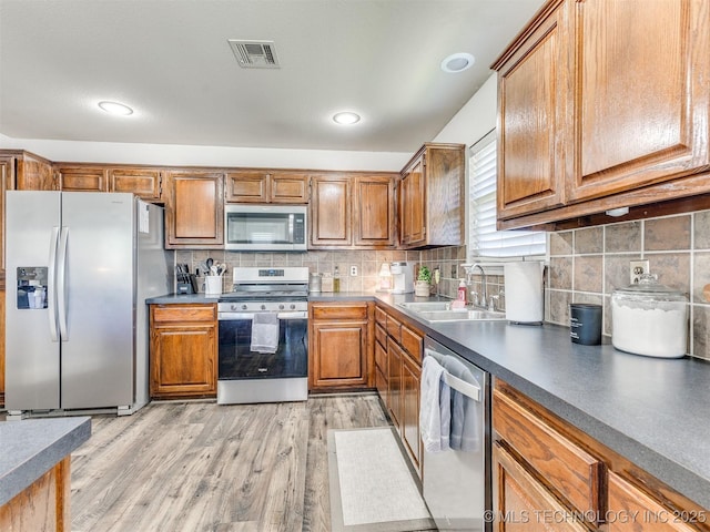 2008 N 8th St, Broken Arrow, OK 74012 - kitchen featuring appliances with stainless steel finishes, a sink, brown cabinetry, and light wood finished floors