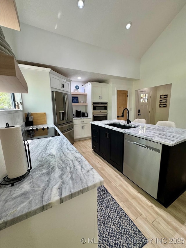 449734 E 356th Rd, Afton, OK 74331 - kitchen with stainless steel appliances, a sink, white cabinets, light wood-type flooring, and a center island with sink