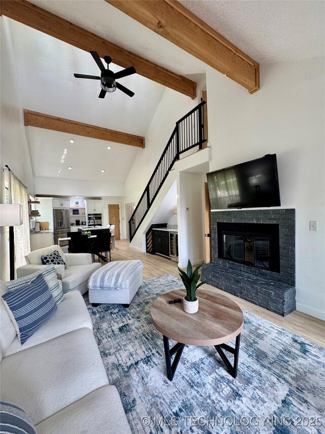 449734 E 356th Rd, Afton, OK 74331 - living room with stairs, ceiling fan, beamed ceiling, light wood-type flooring, and a fireplace