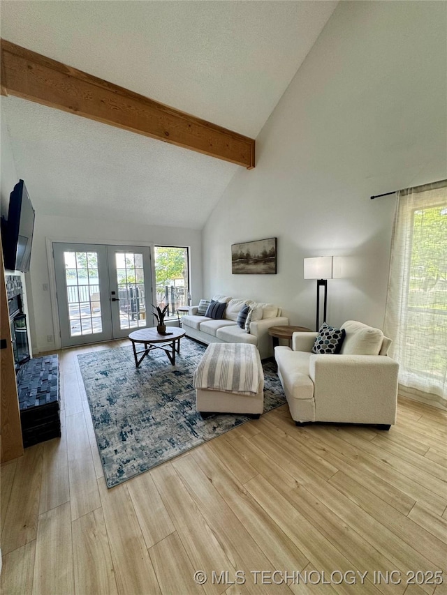 449734 E 356th Rd, Afton, OK 74331 - living room with light wood finished floors, beamed ceiling, french doors, high vaulted ceiling, and a glass covered fireplace