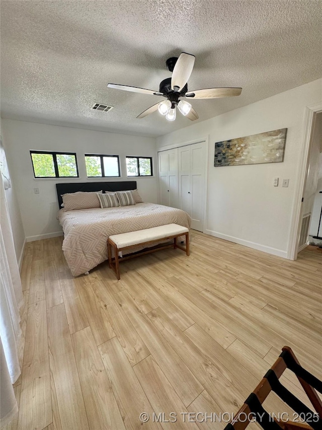 449734 E 356th Rd, Afton, OK 74331 - bedroom featuring light wood-style floors, a textured ceiling, a closet, baseboards, and a ceiling fan