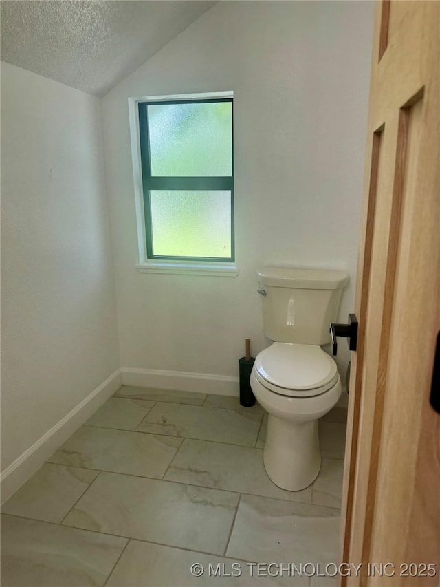 449734 E 356th Rd, Afton, OK 74331 - bathroom featuring a textured ceiling, baseboards, toilet, marble look tile flooring, and lofted ceiling