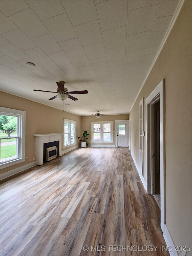 850 E Moses St, Cushing, OK 74023 - unfurnished living room featuring wood finished floors, plenty of natural light, ceiling fan, and a fireplace
