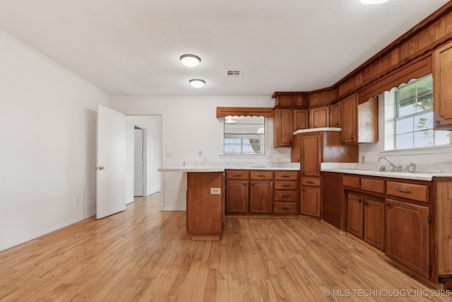 9590 S 4240th Rd, Chelsea, OK 74016 - kitchen featuring a sink, brown cabinetry, light countertops, light wood finished floors, and a textured ceiling