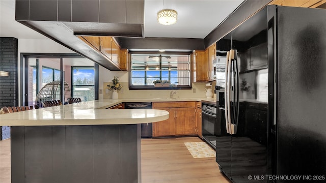 2014 12th Ave NW, Ardmore, OK 73401 - kitchen with black appliances, a peninsula, light countertops, light wood finished floors, and brown cabinets