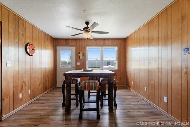 24708 E 18th Rd, Vinita, OK 74301 - dining room featuring wood finished floors, ceiling fan, baseboards, wood walls, and a textured ceiling