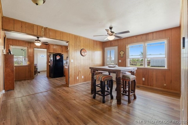 24708 E 18th Rd, Vinita, OK 74301 - dining room featuring a ceiling fan, light wood finished floors, baseboards, and wood walls