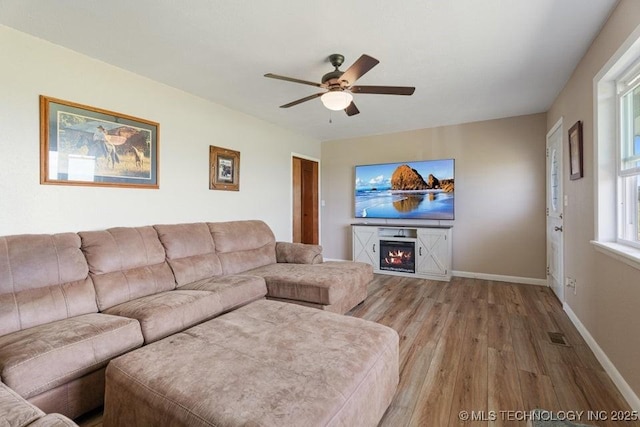 24708 E 18th Rd, Vinita, OK 74301 - living area featuring light wood-type flooring, ceiling fan, a warm lit fireplace, and baseboards