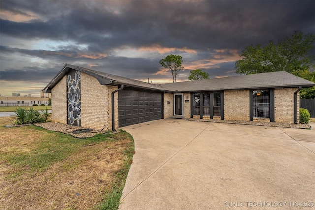 1114 Osage, Ardmore, OK 73401 - view of front of house with brick siding, a garage, driveway, and a front lawn