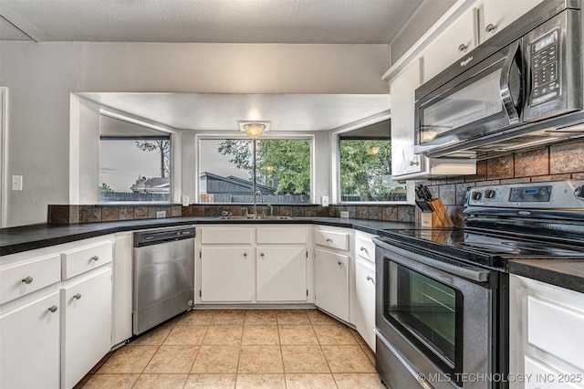 1114 Osage, Ardmore, OK 73401 - kitchen featuring stainless steel appliances, a sink, backsplash, white cabinets, and dark countertops