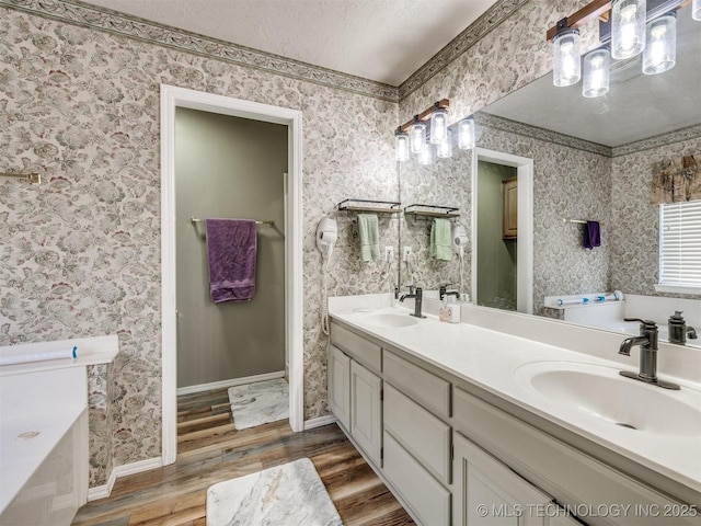 1821 N 11th St, Broken Arrow, OK 74012 - full bathroom featuring wood finished floors, double vanity, a garden tub, a textured ceiling, and baseboards