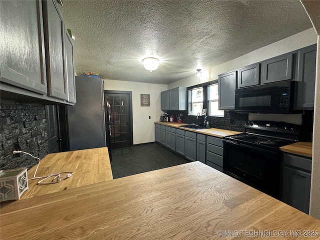 441 SE Carter St, Ardmore, OK 73401 - kitchen featuring black appliances, a sink, baseboards, a textured ceiling, and butcher block counters