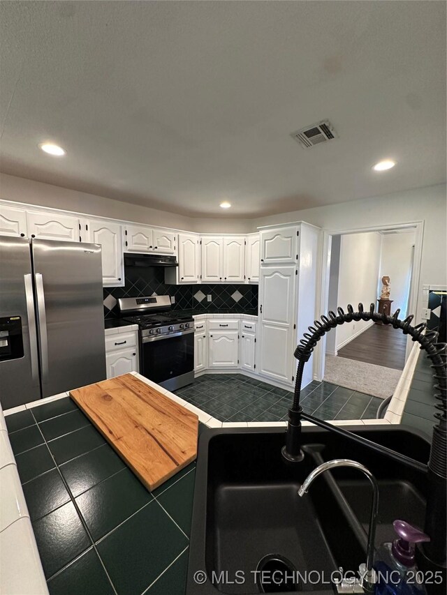 7604 N 127th E Ave, Owasso, OK 74055 - kitchen featuring stainless steel appliances, under cabinet range hood, white cabinets, a sink, and tile counters