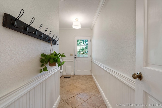8721 S 65th E Pl, Tulsa, OK 74133 - doorway with crown molding, a textured wall, light tile patterned floors, a wainscoted wall, and a decorative wall