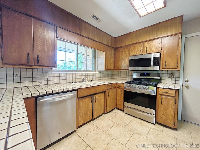 502 W Elm St, Henryetta, OK 74437 - kitchen with stainless steel appliances, backsplash, tile countertops, and light tile patterned floors