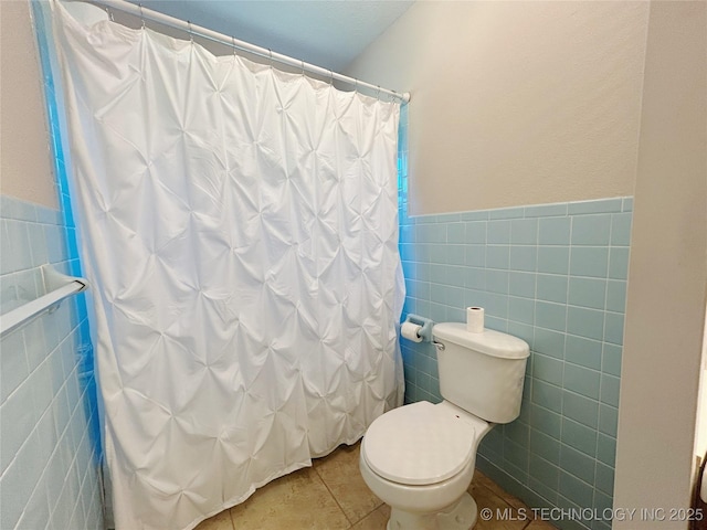 502 W Elm St, Henryetta, OK 74437 - full bathroom with tile walls, tile patterned floors, a wainscoted wall, and a shower with curtain