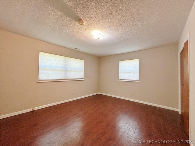 502 W Elm St, Henryetta, OK 74437 - unfurnished bedroom with dark wood finished floors and a textured ceiling