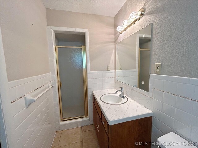 502 W Elm St, Henryetta, OK 74437 - bathroom with tile walls, vanity, a shower stall, tile patterned flooring, and wainscoting