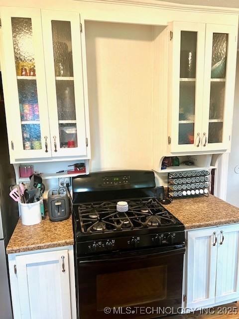 2201 Baugh St, Muskogee, OK 74403 - kitchen with black gas range oven, white cabinets, and glass insert cabinets