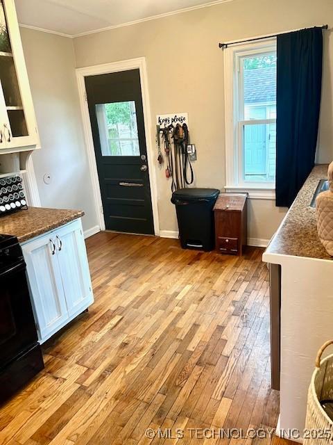 2201 Baugh St, Muskogee, OK 74403 - kitchen featuring black gas stove, white cabinetry, crown molding, light wood-style floors, and glass insert cabinets